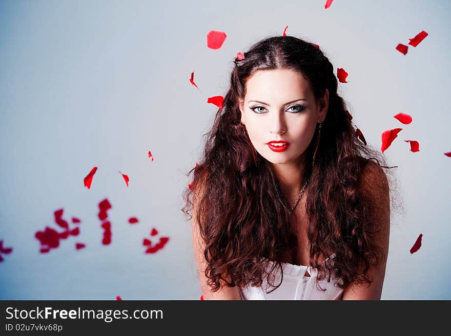 Young beautiful woman with petals of roses, on a white background