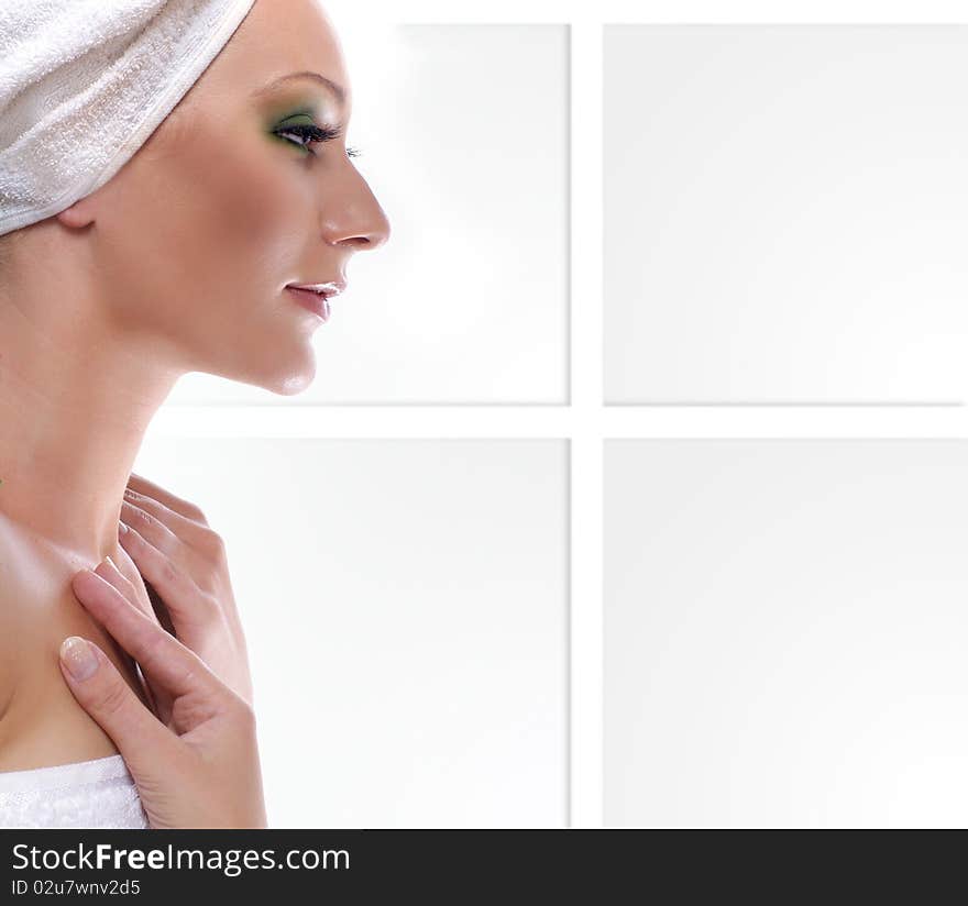 Portrait of a young and cute woman in a towel. The image is isolated on a light abstract background.