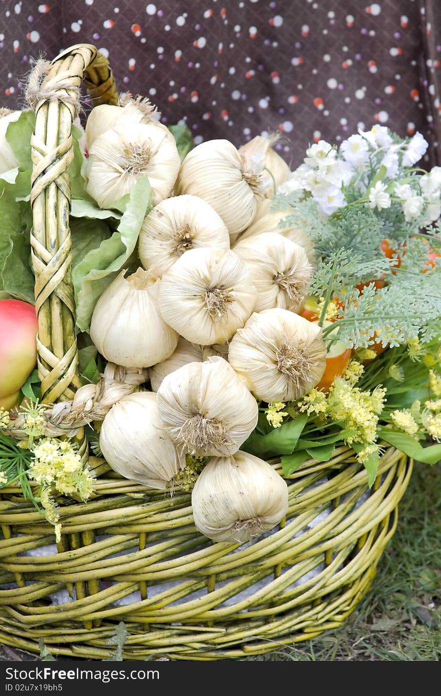 The basket with garlic and greens costs on a grass