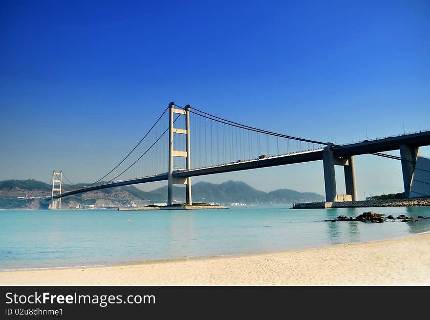 Bridge crossing the sea to an island under a clear blue sky just next to a white sand beach. Bridge crossing the sea to an island under a clear blue sky just next to a white sand beach.