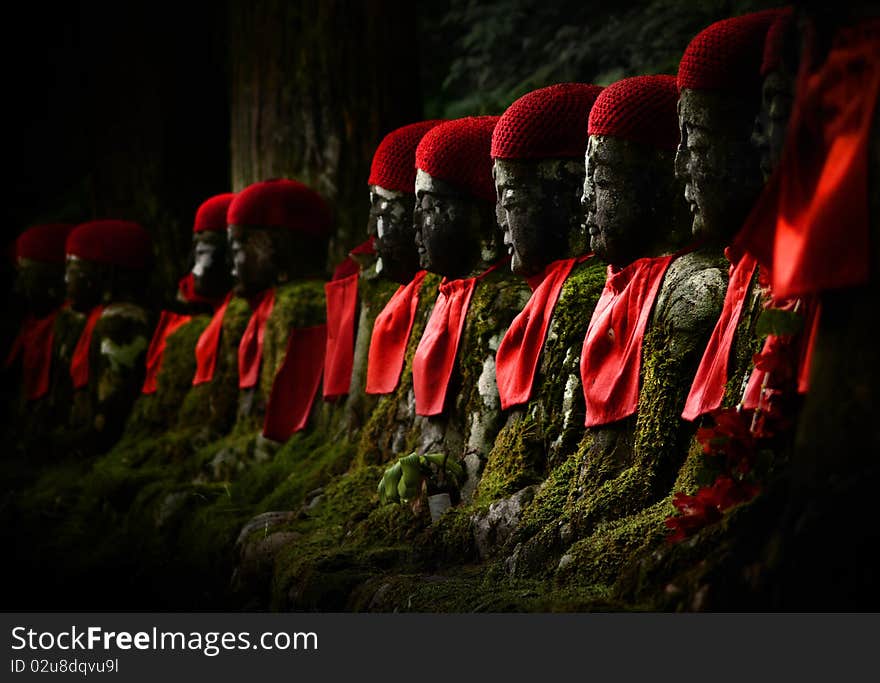 Stone budhhas with red hat side by side in the forest. Stone budhhas with red hat side by side in the forest.