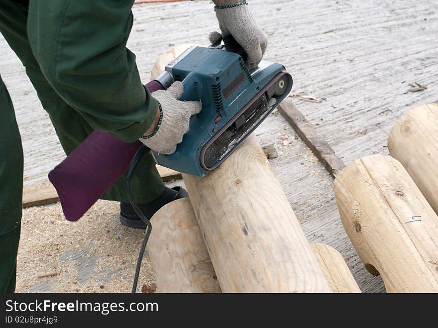 Carpenter smoothing the log on the construction. Carpenter smoothing the log on the construction