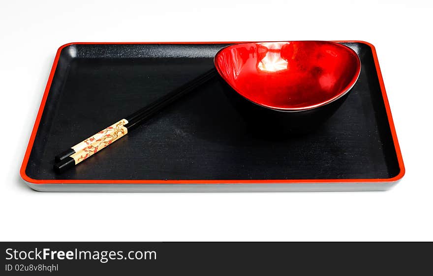 Two chop sticks and a red and black bowl. Two chop sticks and a red and black bowl