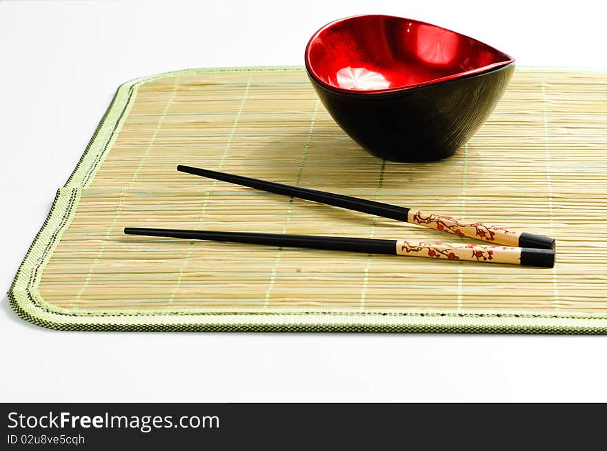 Two chop sticks and a red and black bowl. Two chop sticks and a red and black bowl