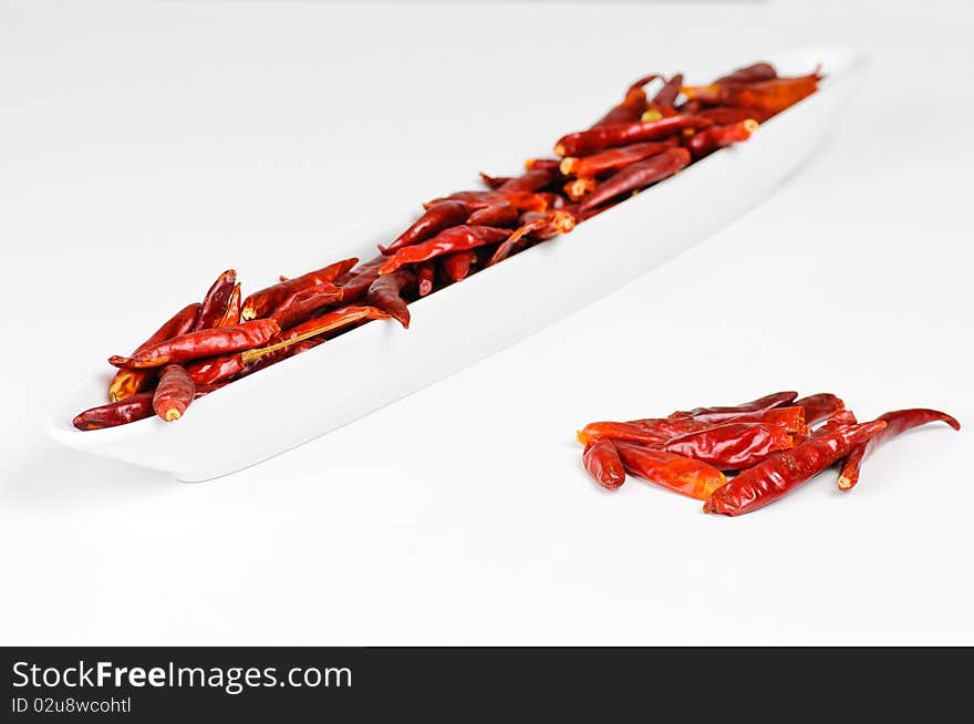 A bowl with some dried chili fruits with an additional pile next to it.