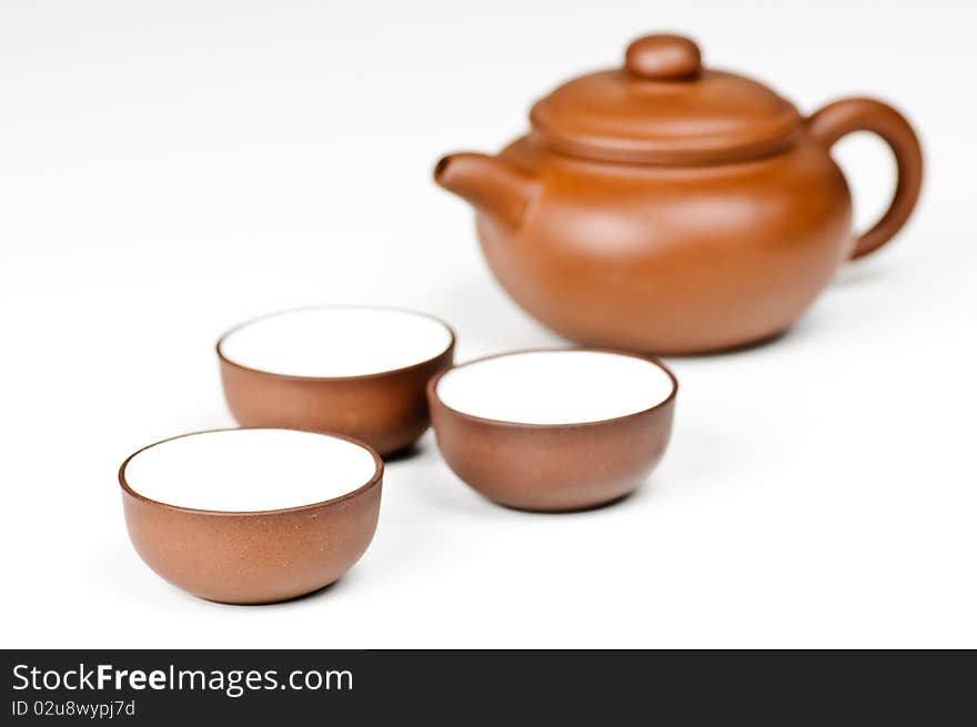 Clay tea cups with a tea pot in the background