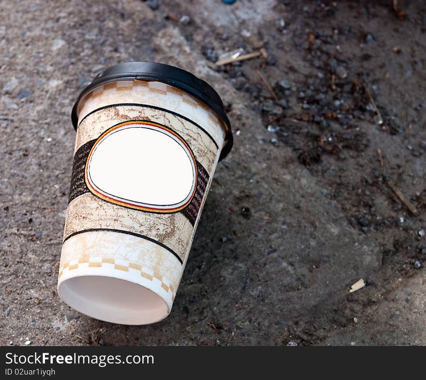 Paper coffee cup with plastic lid sitting on the sidewalk. Paper coffee cup with plastic lid sitting on the sidewalk