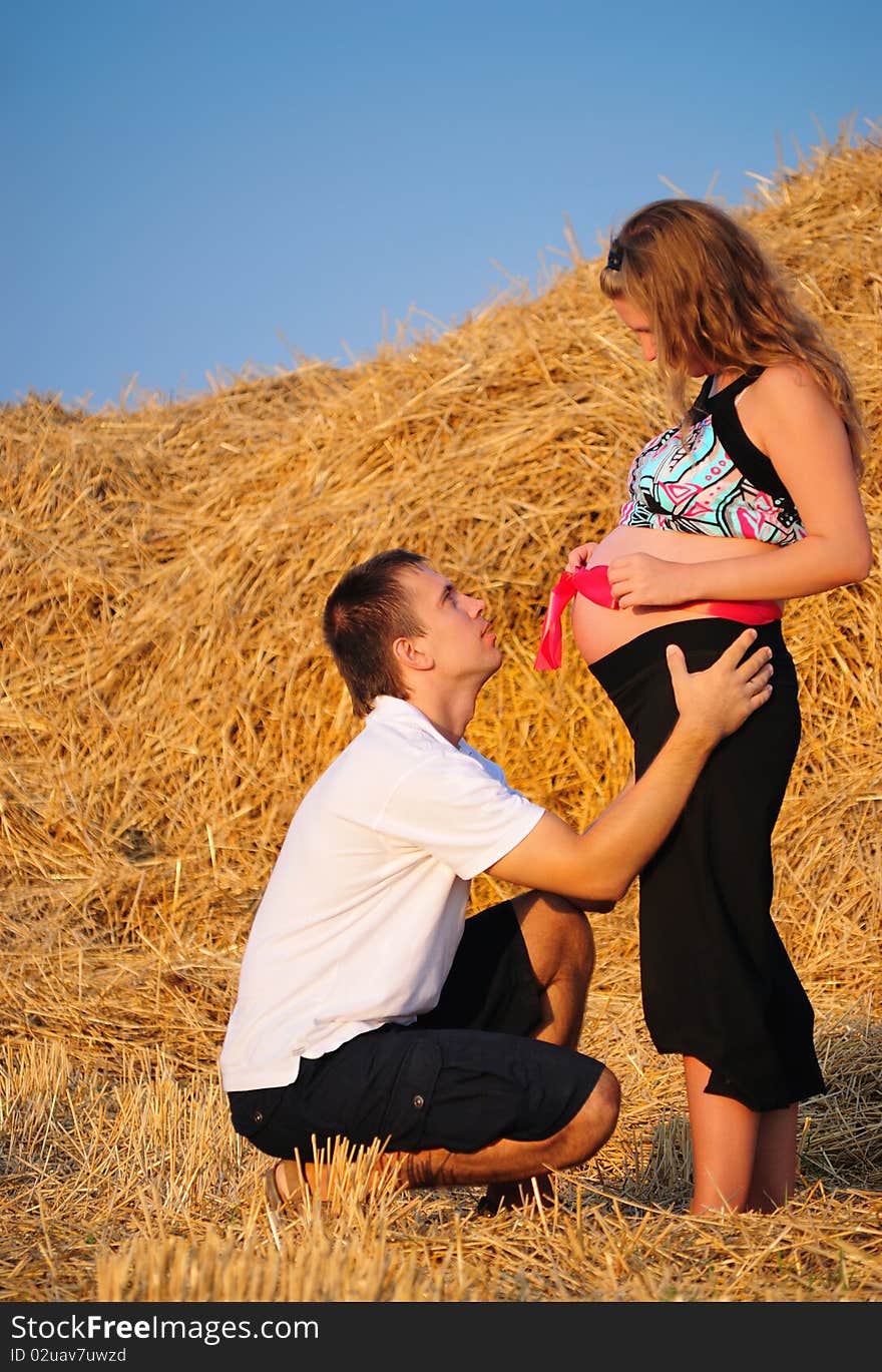 The guy embraces the pregnant girl with a gift in a stomach. The guy embraces the pregnant girl with a gift in a stomach