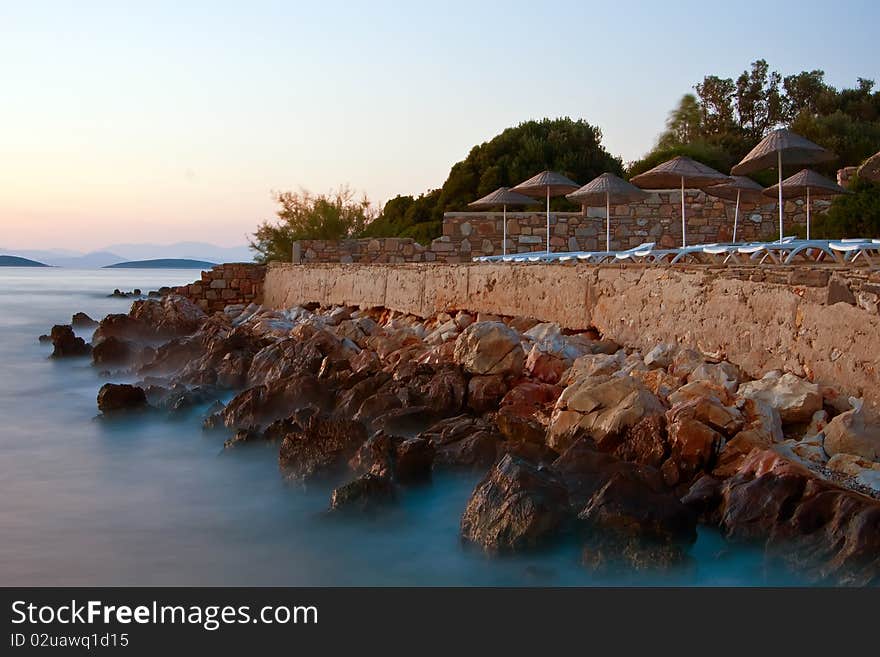 Beach at the Aegean sea with beach chairs and umbrellas in evening. Beach at the Aegean sea with beach chairs and umbrellas in evening