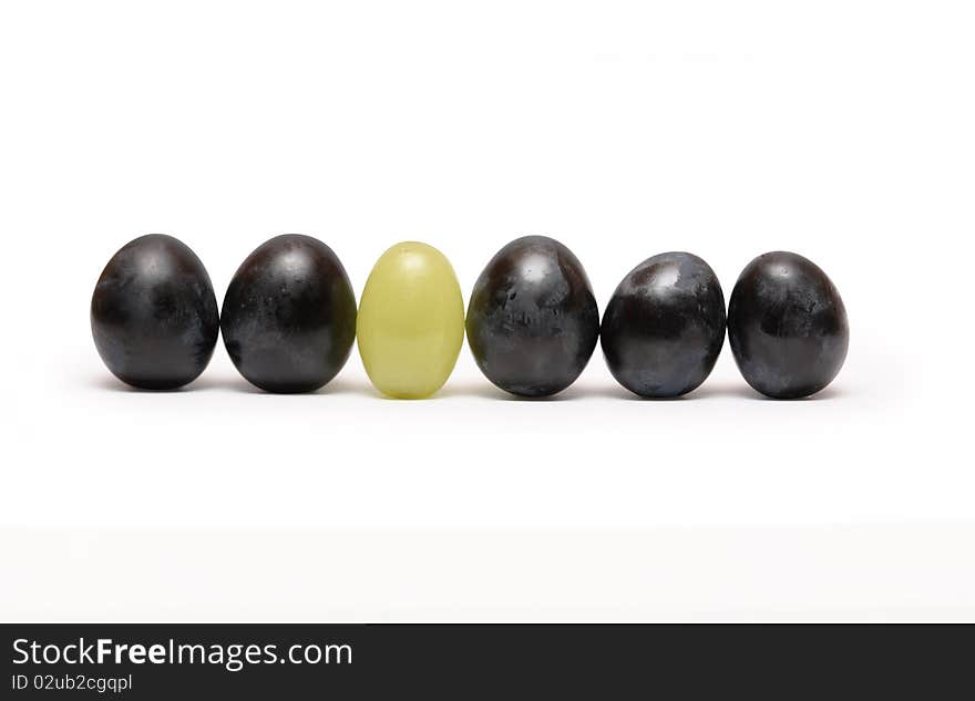 Few red and one green grapes berries standing in a row. Isolated on white background with clipping path. Few red and one green grapes berries standing in a row. Isolated on white background with clipping path