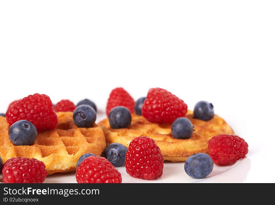 Belgian waffles with fresh raspberries and blueberries on white plate. Belgian waffles with fresh raspberries and blueberries on white plate