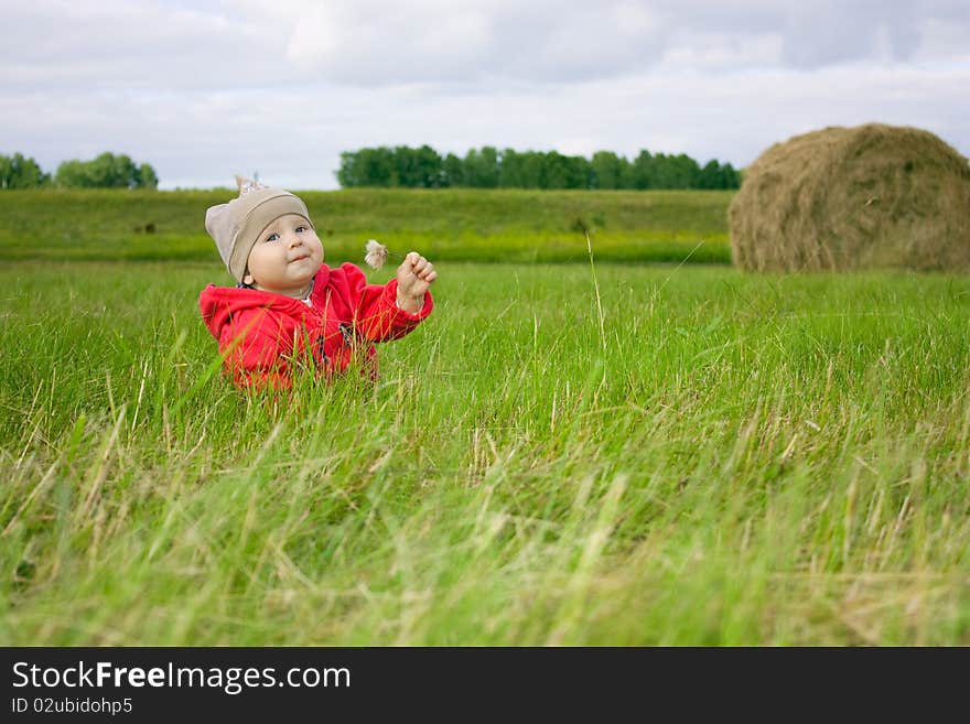 Little girl sitting in field with flower in hand