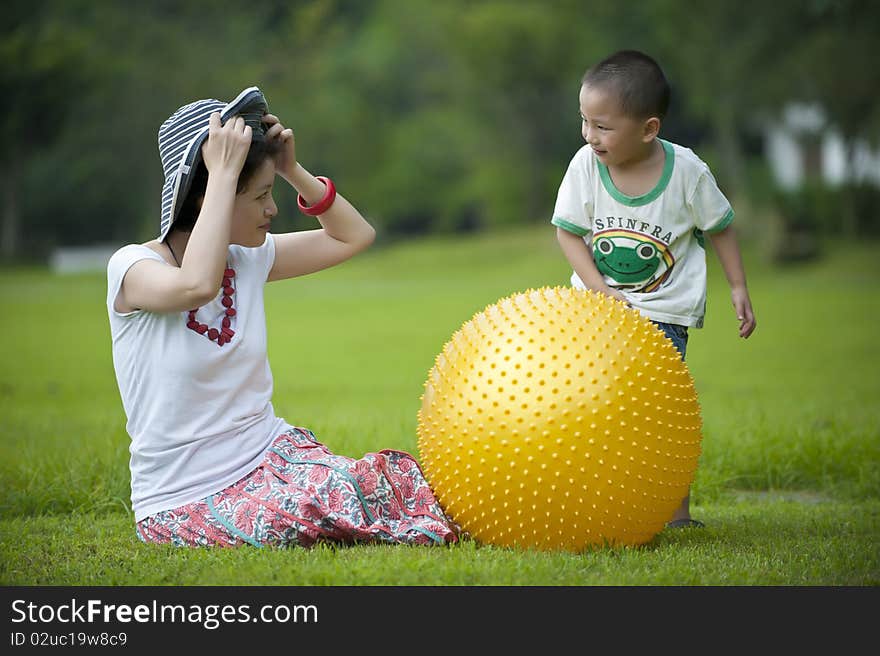 Mother and son play ball in grass