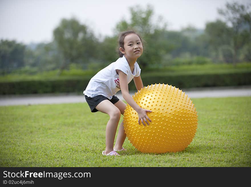 Asian girl play ball on grass