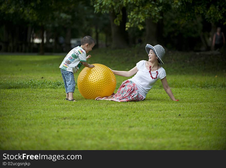 Mother and son in grass and paly yellow ball. Mother and son in grass and paly yellow ball