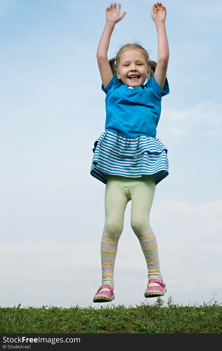 Little girl jump om grass under sky