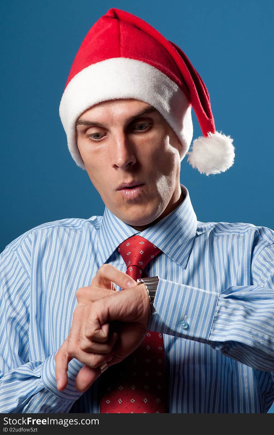 Young man in red christmas hat look at his hand's clock