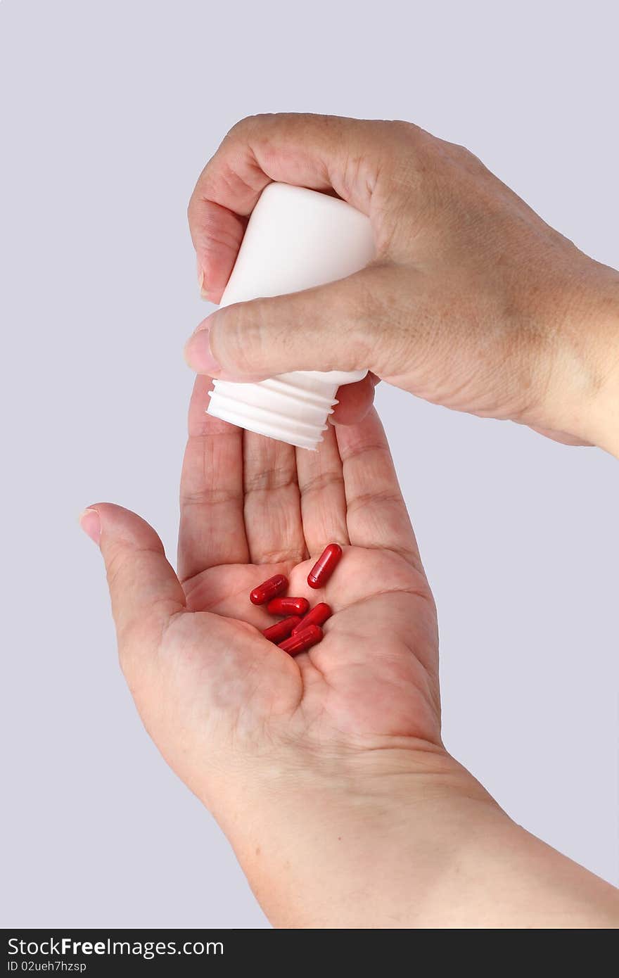 Hands Of Old Woman Taking Pills Isolated With Gray Background