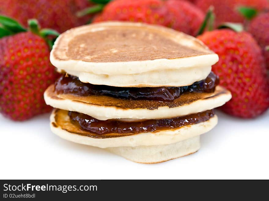 Closeup of pancakes and strawberry jam with whole strawberries in the background. Closeup of pancakes and strawberry jam with whole strawberries in the background