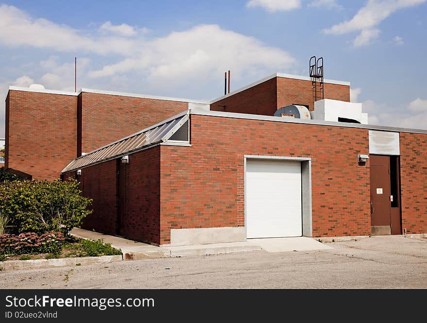 Exterior of brick industrial building, with loading dock, shot on a bright sunny day.