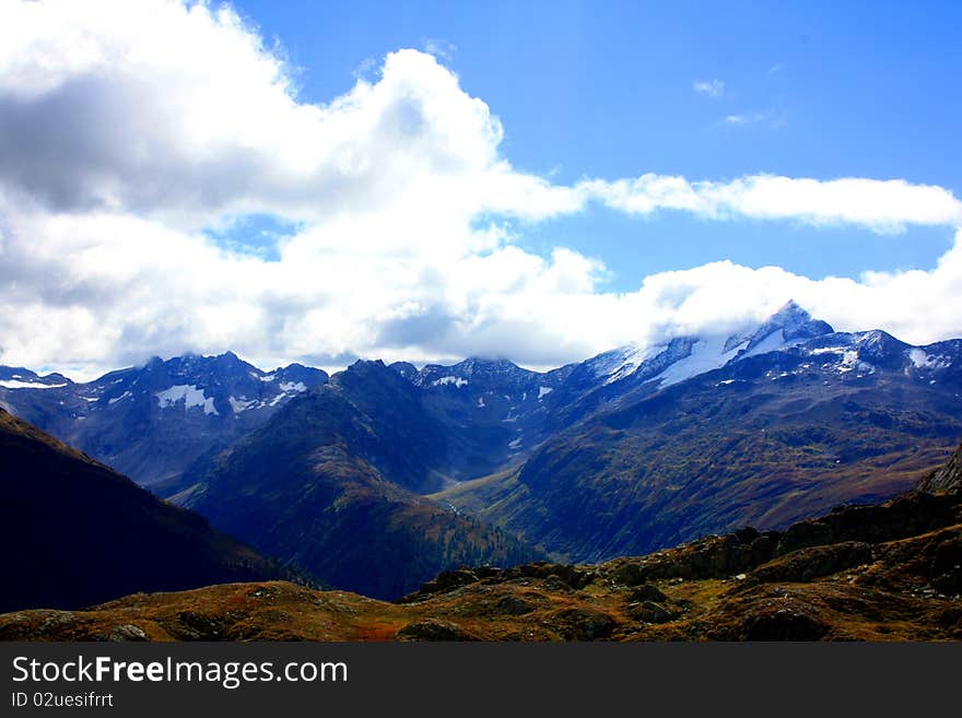 A snow capped mountain in Switzerland overlooking a green valley. A snow capped mountain in Switzerland overlooking a green valley