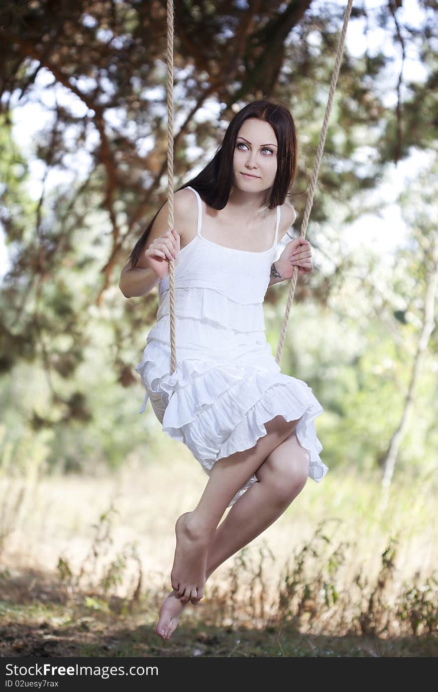 Young woman swinging outdoor in summer