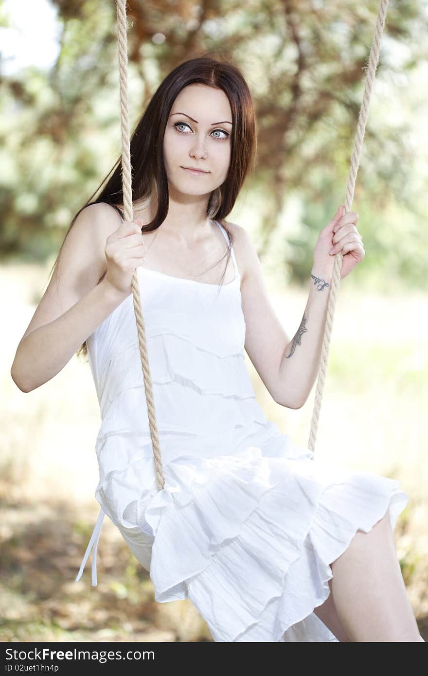 Young woman swinging outdoor in summer