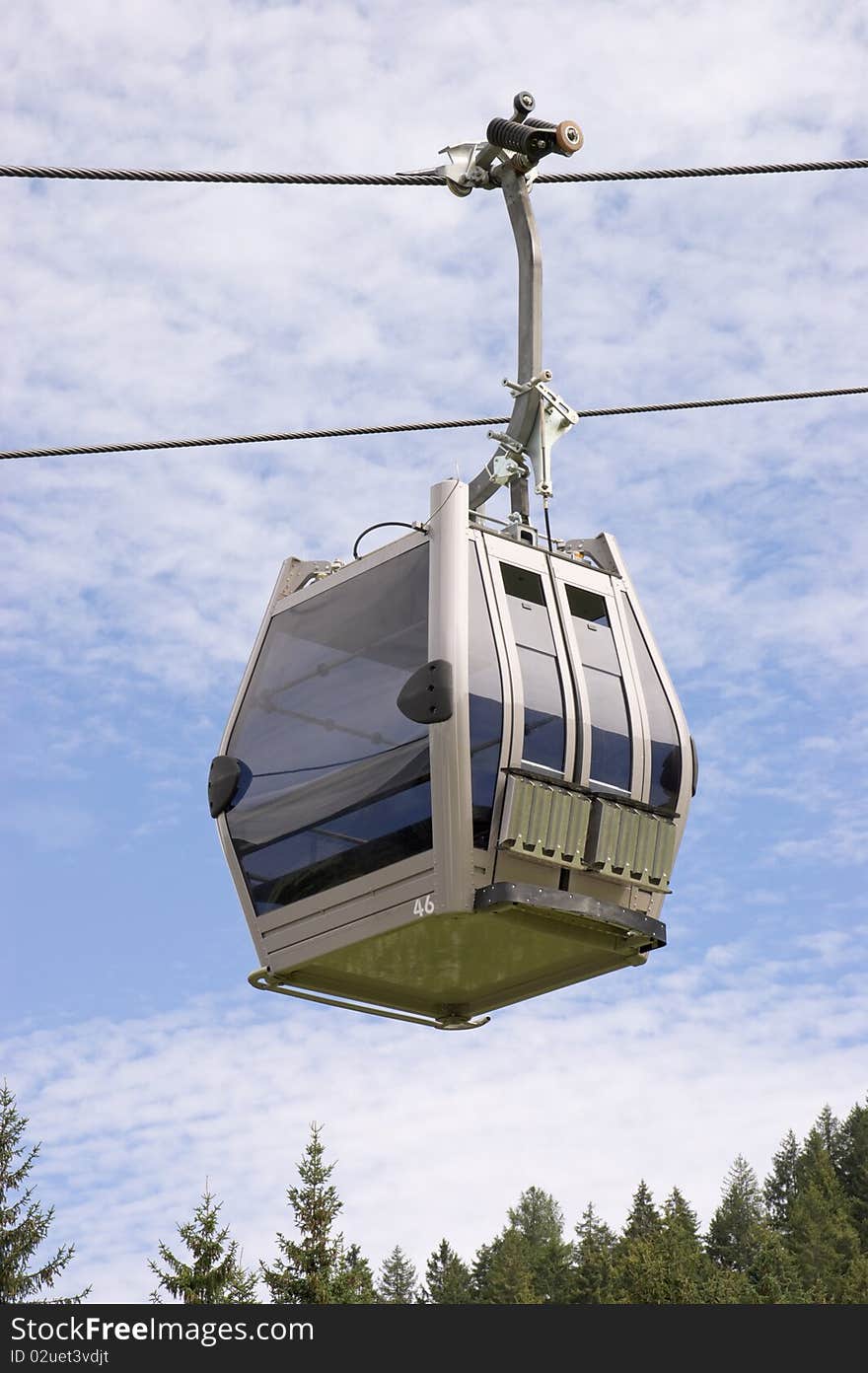 Cable car on a cable way against a cloudy blue sky. Cable car on a cable way against a cloudy blue sky