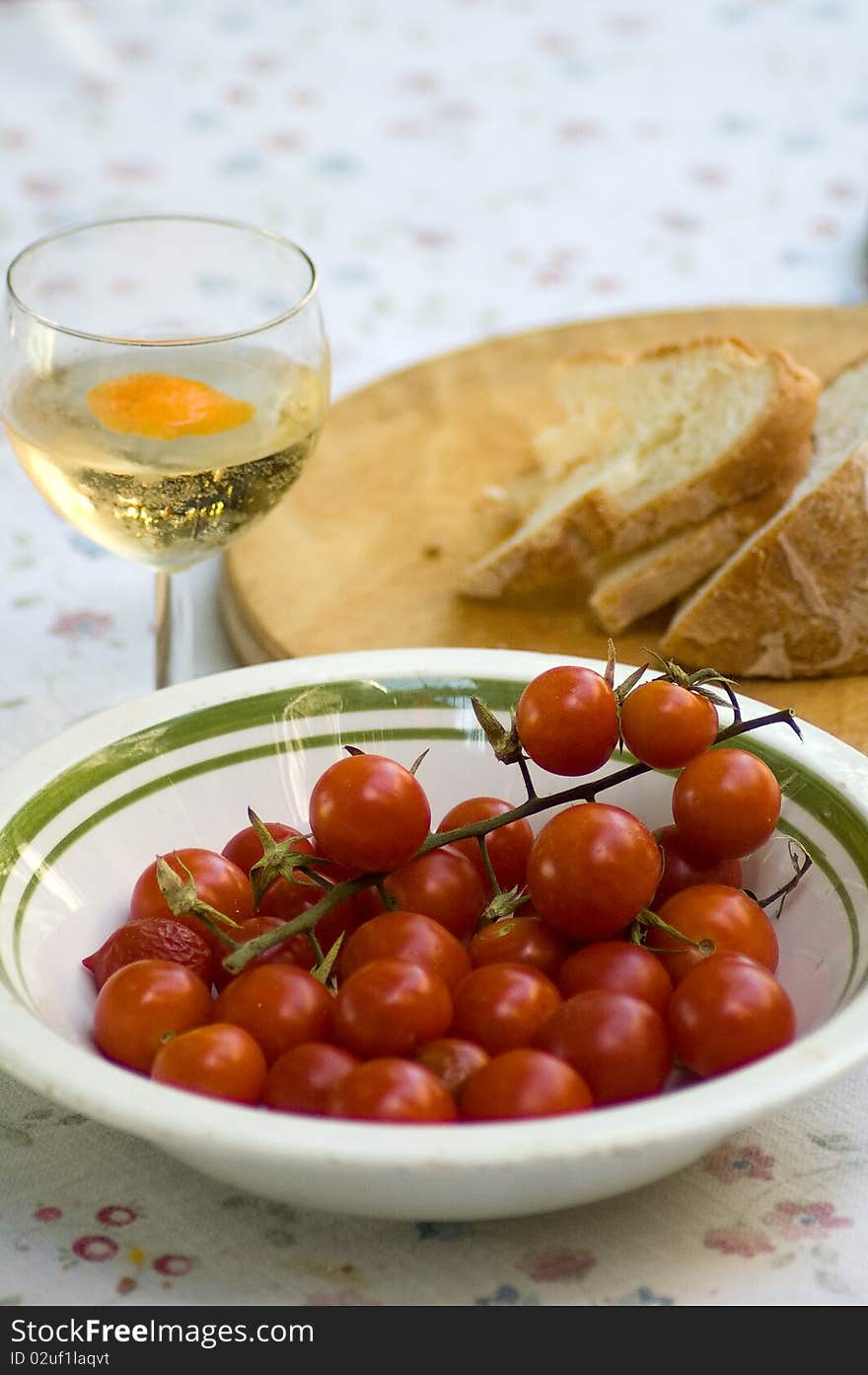 Mediterranean tomatoes appetizer with bread and white wine on set table.