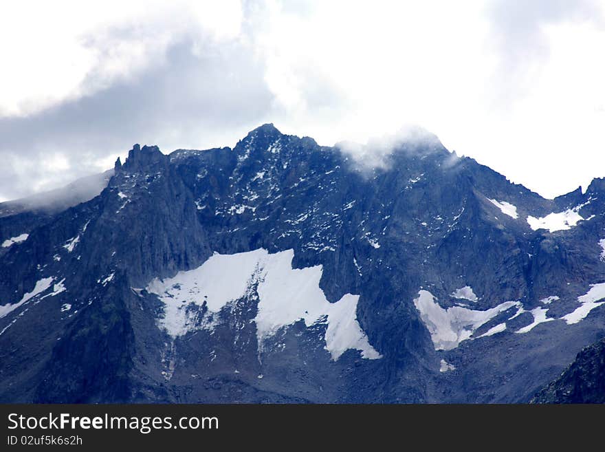 A snow capped mountain in Switzerland with Clouds Gathering. A snow capped mountain in Switzerland with Clouds Gathering