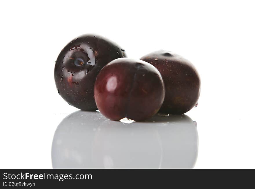 Three big fresh plums with reflection isolated on white