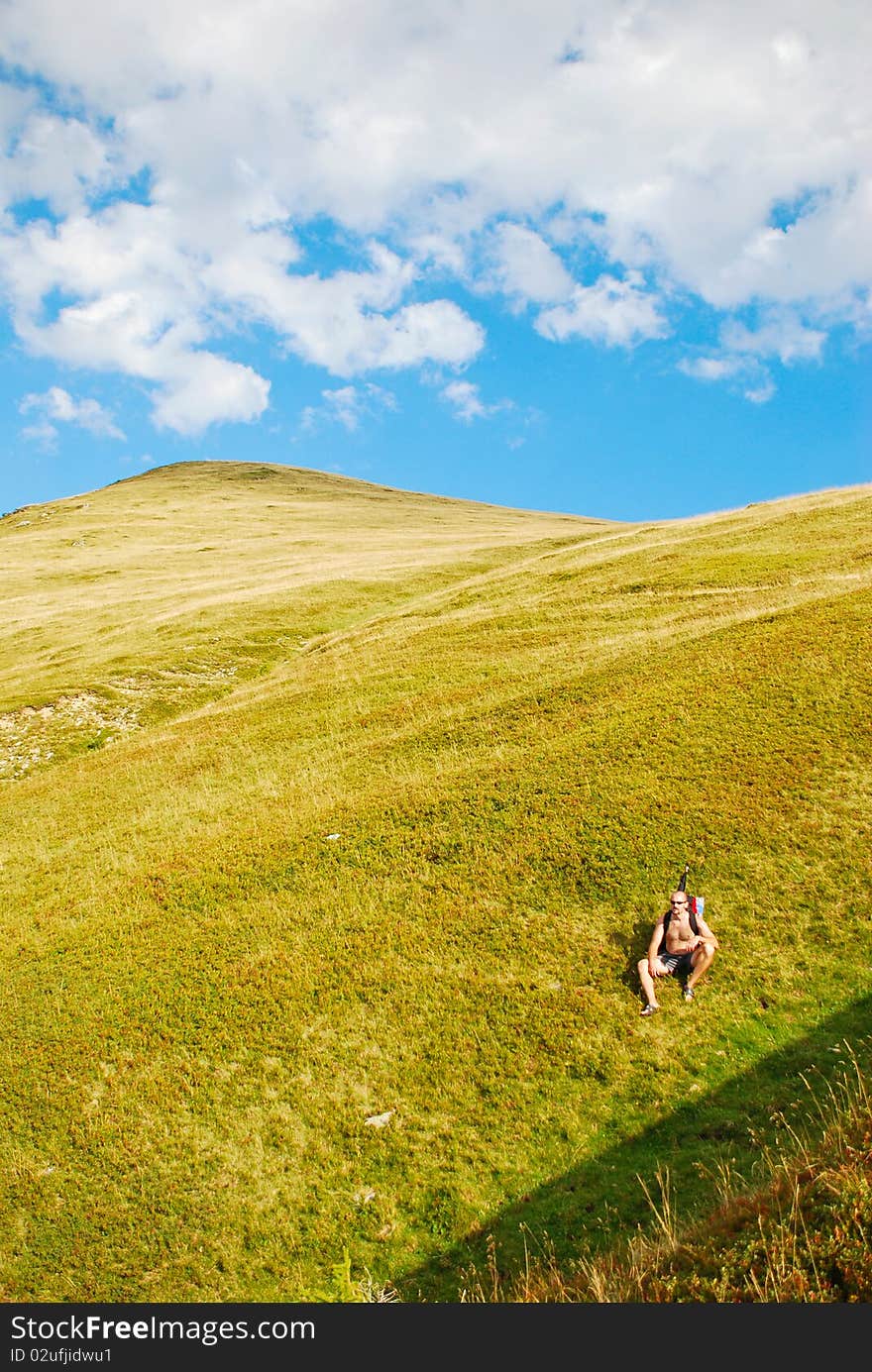 Tired hiker resting on mountain slope