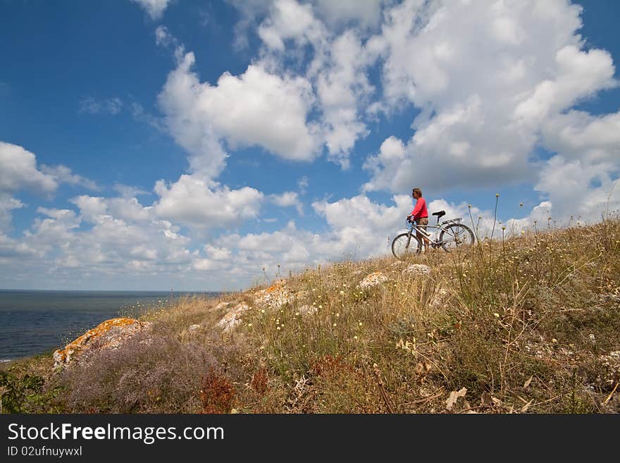 Women with bike on meadow on sky background. Women with bike on meadow on sky background