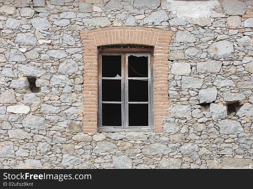 The wall of an old house in ruins with a broken window. The wall of an old house in ruins with a broken window