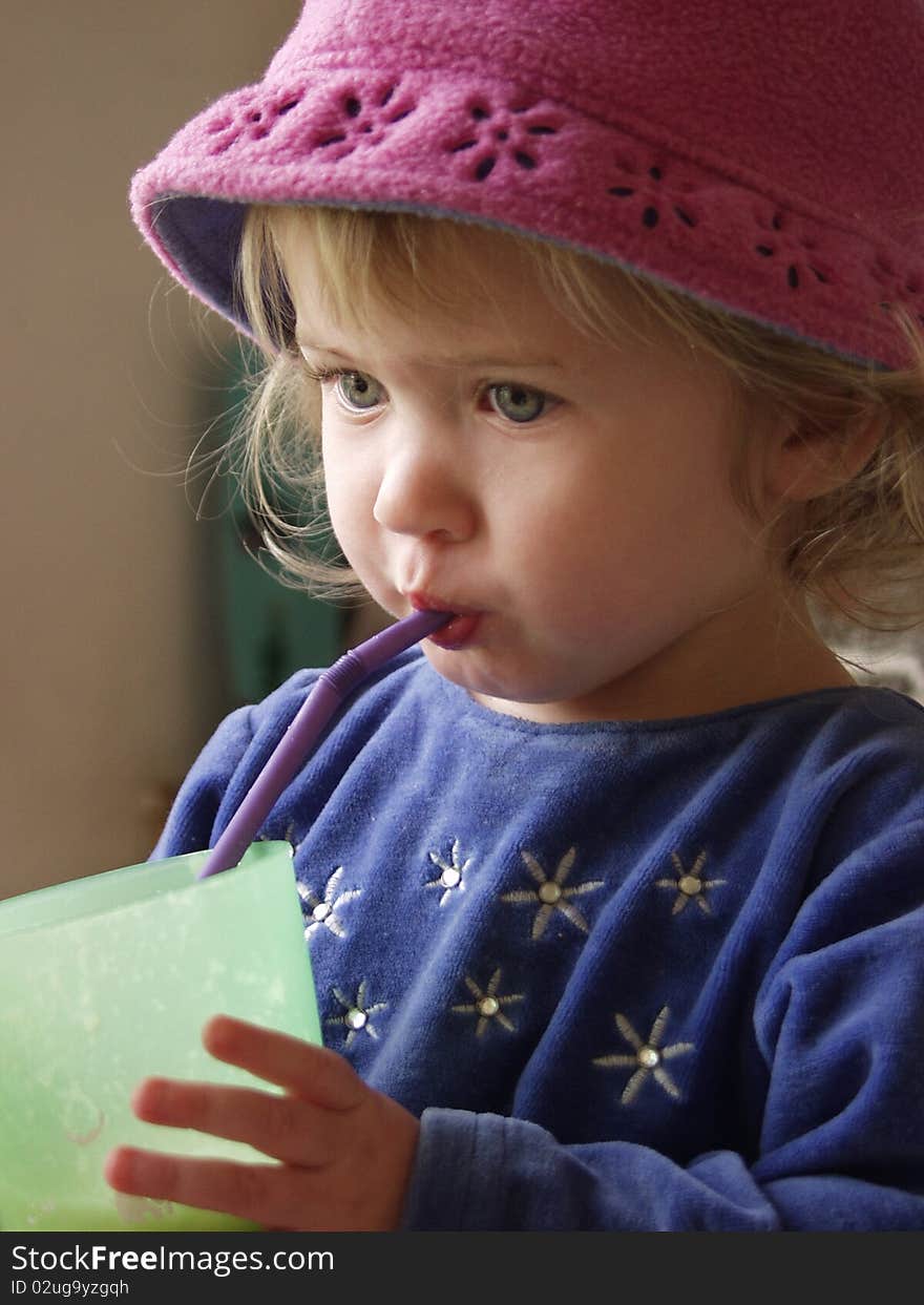 20 month old girl in fleece hat, drinking from straw. 20 month old girl in fleece hat, drinking from straw