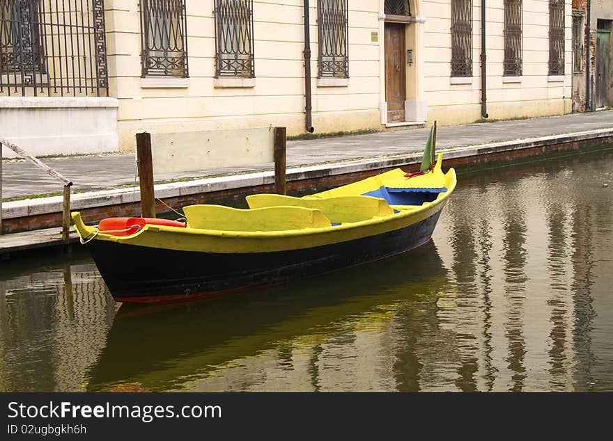 Blue and yellow boat along a canal of Comacchio