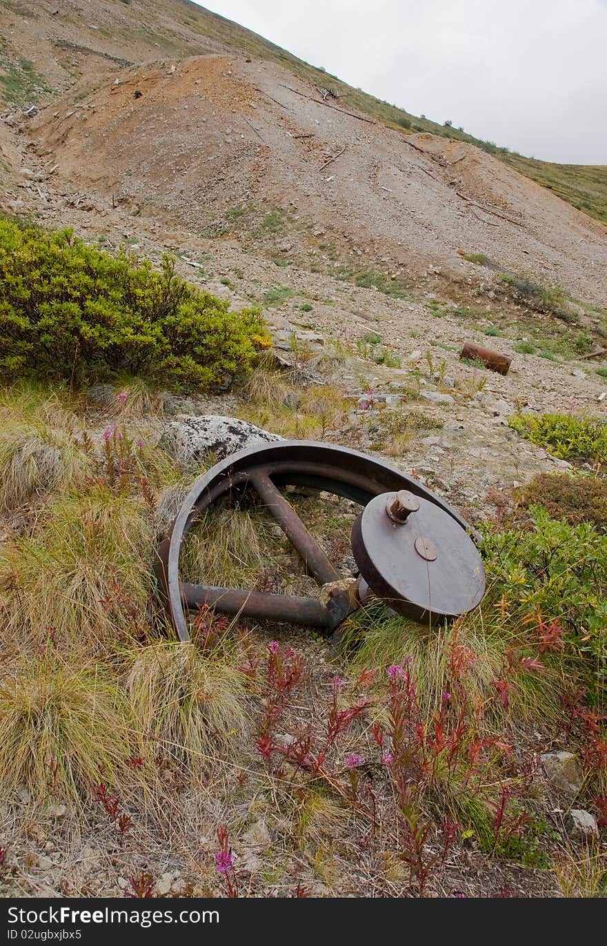 A large gear wheel lies abandoned near mining tailings in Yukon Territory. A large gear wheel lies abandoned near mining tailings in Yukon Territory