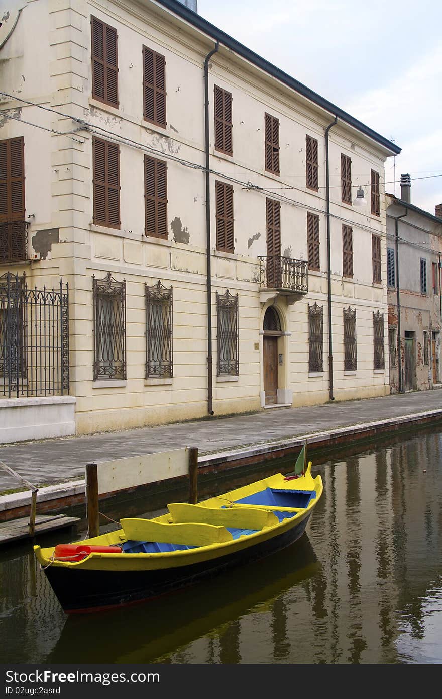 Blue and yellow boat along a canal of Comacchio