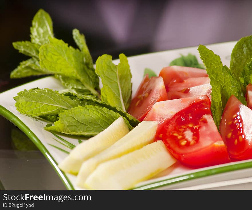 Dish of various vegetables such as tomatoes, cucumbers and mint