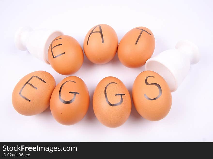 Eggs with an inscription EAT EGGS and egg holders on white background
