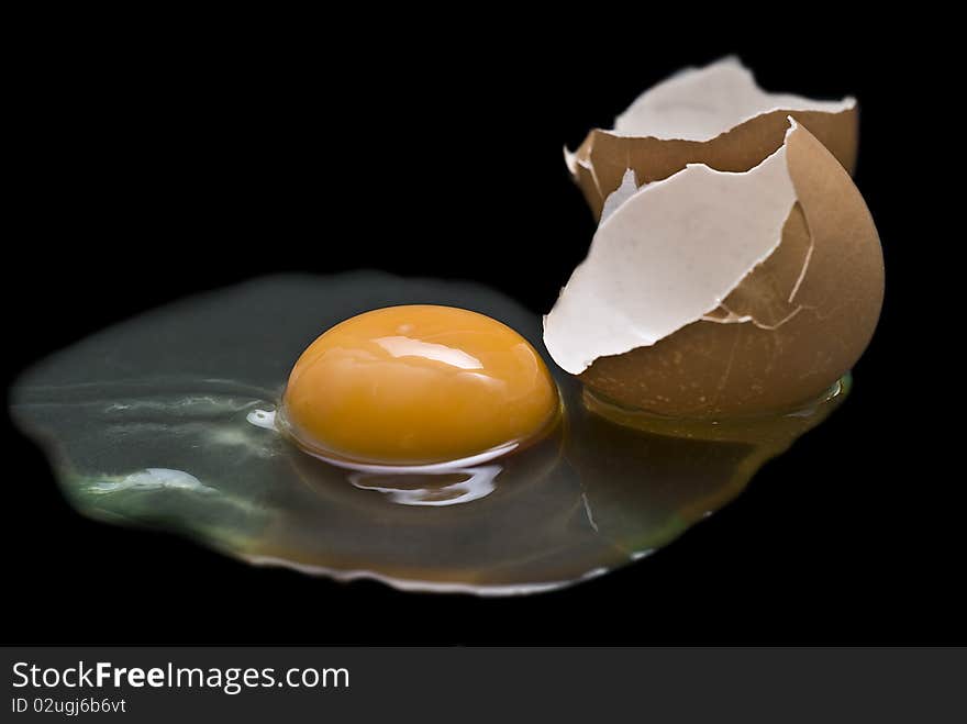 A cracked raw egg on a black background. A cracked raw egg on a black background.