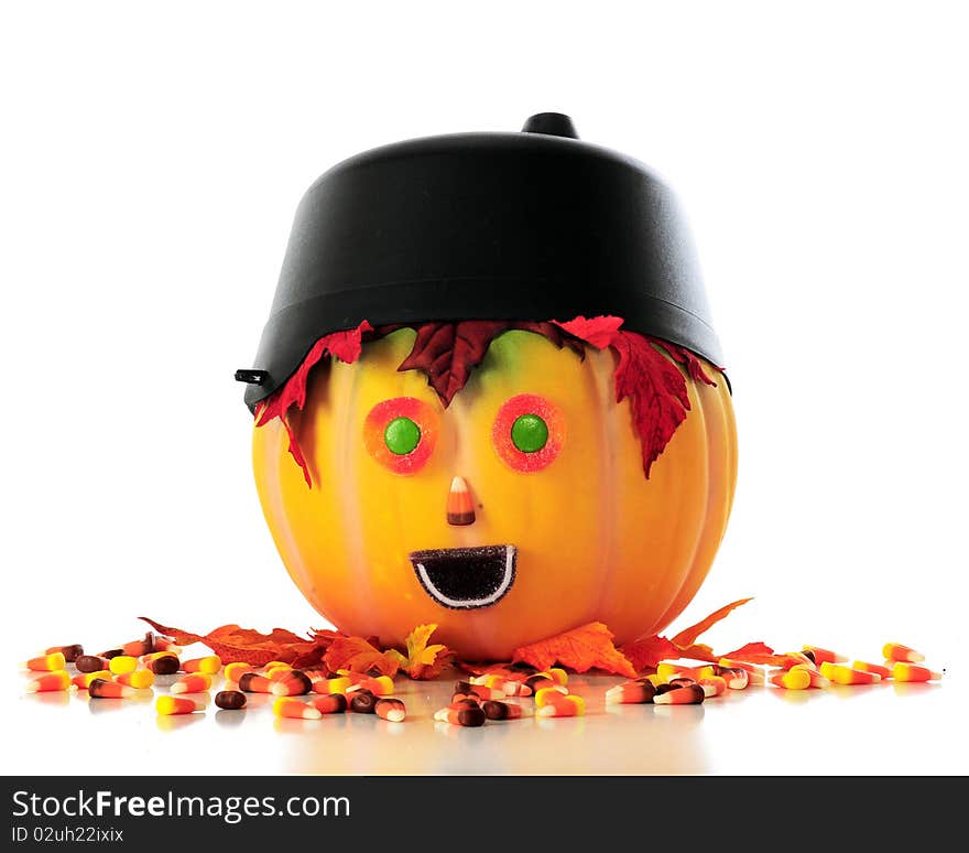 A pumpkin head with a cauldron hat, leaf hair and halloween candy face, surrounded by spilled candy corn.. Isolated on white. A pumpkin head with a cauldron hat, leaf hair and halloween candy face, surrounded by spilled candy corn.. Isolated on white.