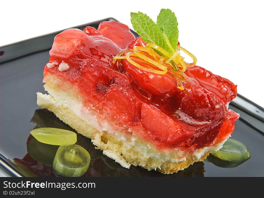 Cheesecake with strawberries on black plate isolated. Cheesecake with strawberries on black plate isolated