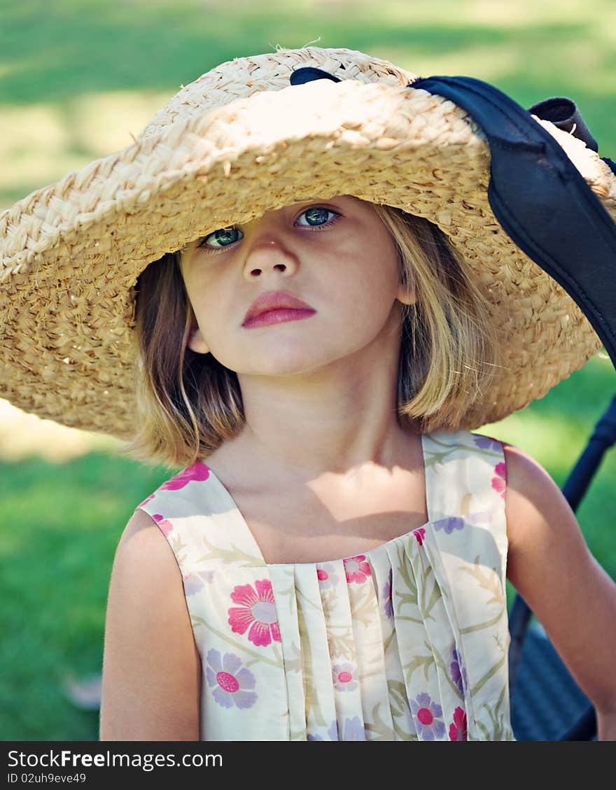 Girl age 4 wearing large straw hat and flowered dress outdoors. Girl age 4 wearing large straw hat and flowered dress outdoors