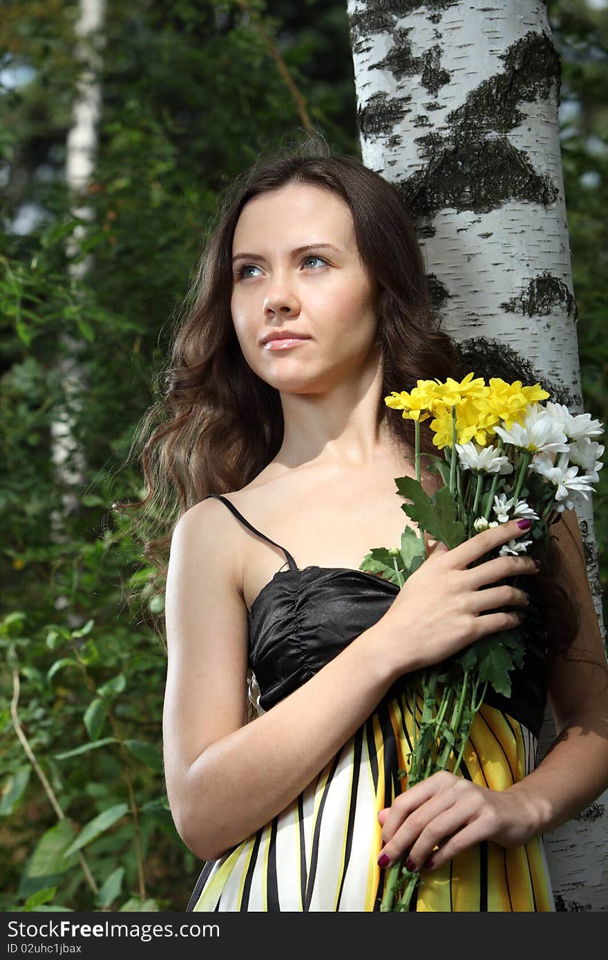 Girl with a flower bunch near a birch. Girl with a flower bunch near a birch