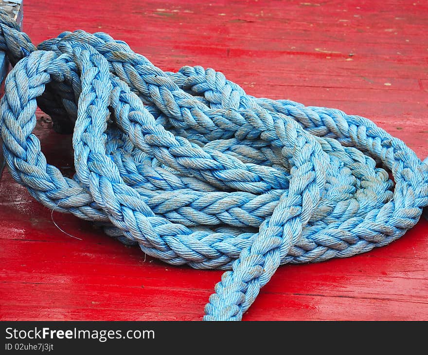 Blue rope coiled on the deck of an old red boat. Blue rope coiled on the deck of an old red boat