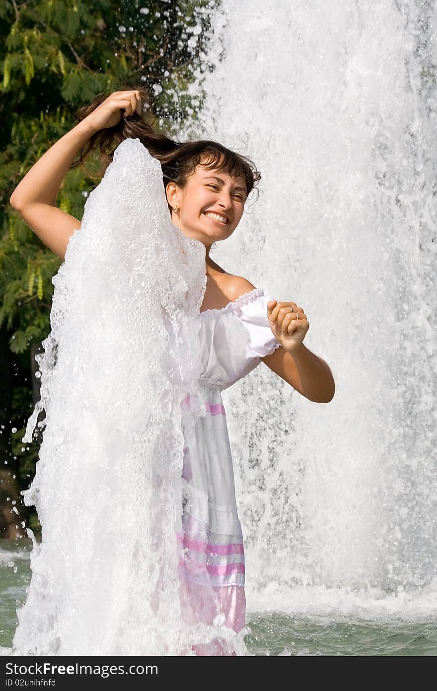 Happy young girl in the fountain