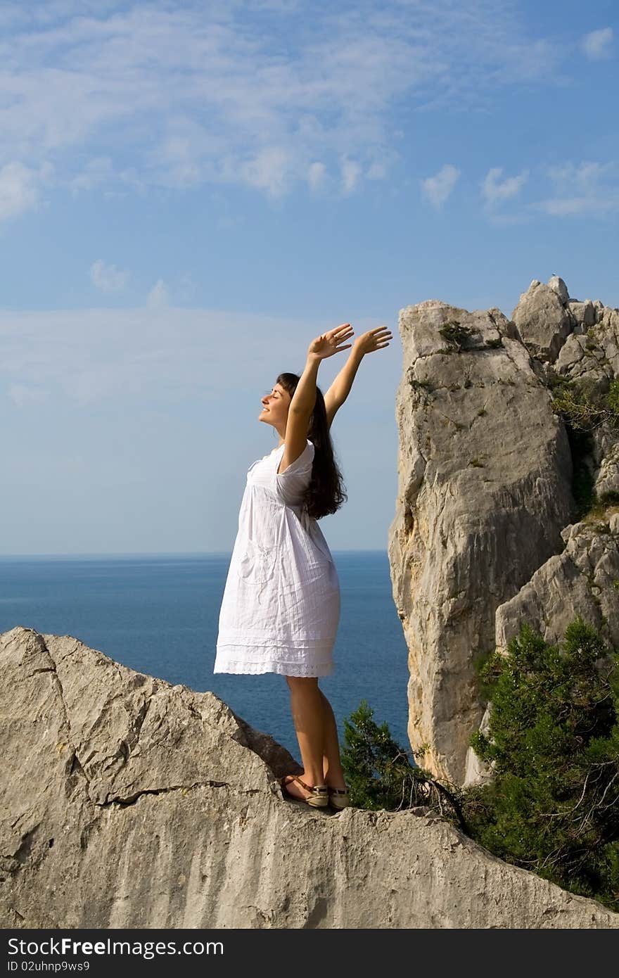 Happy young girl standing on the rocks