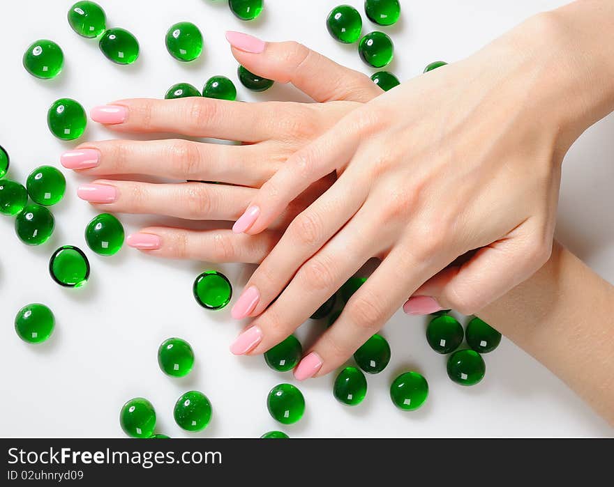 Beautiful hands with perfect nail pink manicure and green decorative stones. isolated on white background