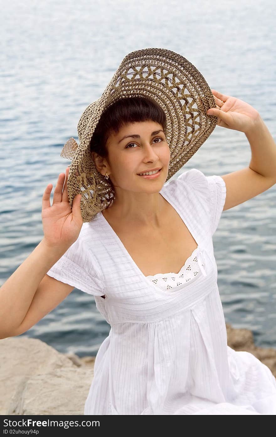 Happy young girl in the bonnet near the sea